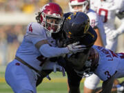 California running back Jaydn Ott, center, is tackled by Washington State defensive backs Kapena Gushiken, left, and Cam Lampkin during the first half of an NCAA college football game Saturday, Nov. 11, 2023, in Berkeley, Calif. (AP Photo/Godofredo A.
