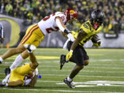 Oregon running back Bucky Irving (0) tries to get away form Southern California linebacker Tackett Curtis (25) during the first half of an NCAA college football game Saturday, Nov. 11, 2023, in Eugene, Ore.