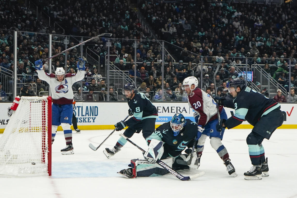 Colorado Avalanche center Ross Colton (20) watches his goal against Seattle Kraken goaltender Joey Daccord (35) as Avalanche right wing Mikko Rantanen, far left, reacts during the second period of an NHL hockey game, Monday, Nov. 13, 2023, in Seattle.