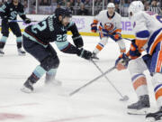 Seattle Kraken right wing Oliver Bjorkstrand (22) works to control the puck with New York Islanders' Noah Dobson (8) defending during the second period of an NHL hockey game Thursday, Nov. 16, 2023, in Seattle.