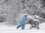 A pedestrian pushes a shopping cart on Cordova Street during a heavy snowfall, Thursday, Nov. 9, 2023 in Anchorage, Alaska. Four homeless people have died in Anchorage in the last week, underscoring the city&rsquo;s ongoing struggle to house a large houseless population at the same time winter weather has returned, with more than 2 feet (0.61 meters) of snow falling within 48 hours.