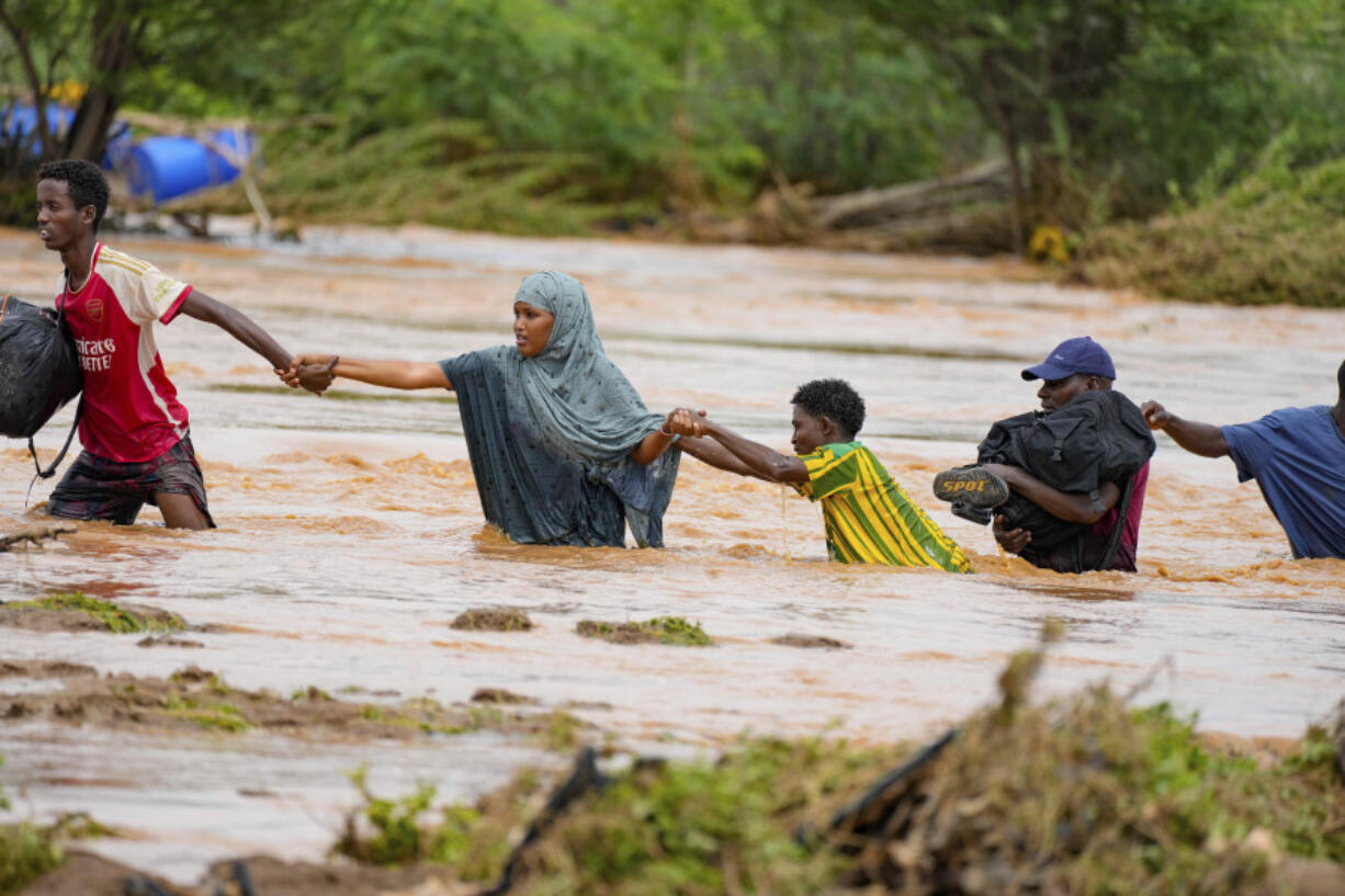 FILE - Residents cross a road damaged during flooding in Tula, Tana River county in Kenya on Nov. 25, 2023.