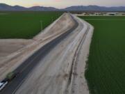 A truck hauling hay drives near Al Dahra Farms, Tuesday, Oct. 17, 2023, in the McMullen Valley in Wenden, Ariz. Worries about future water supplies from ancient aquifers are bubbling up in western rural Arizona. Some neighbors complain that their backyard wells have dried up since the Emirati agribusiness began farming alfalfa nearby.