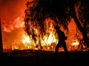 A photojournalist walks among the flames of a wildfire in rural Aguanga, Calif. Monday, Oct. 30, 2023.