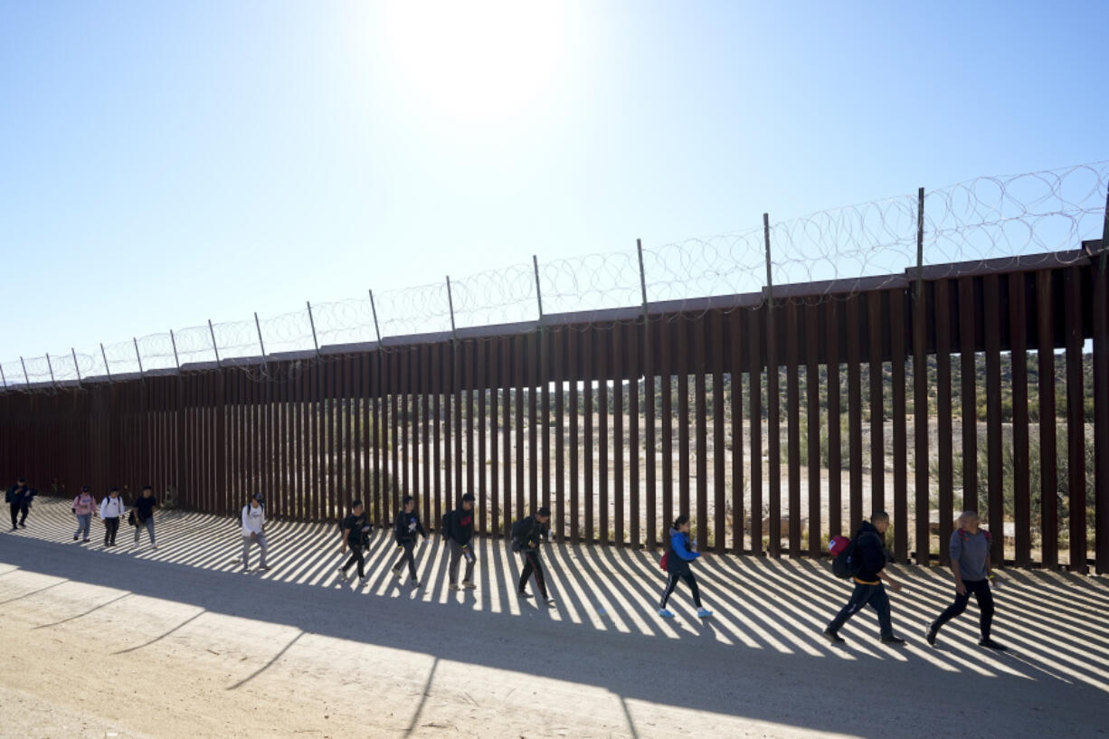 FILE - A group of people, including many from China, walk along the wall after crossing the border with Mexico to seek asylum, Tuesday, Oct. 24, 2023, near Jacumba, Calif. As Congress returns this week, Senate Republicans have made it clear they won&rsquo;t support additional war aid for Ukraine unless they can pair it with border security measures.