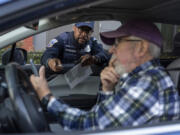 Metropolitan Police Department officer Muhammad Lewis explains to Nils Bruzelius how to use a Tile tracker during an event where police officers distributed mobile tracking devices for cars to drivers in an attempt to curb a rise in crime in Washington on Tuesday, Nov. 7, 2023.