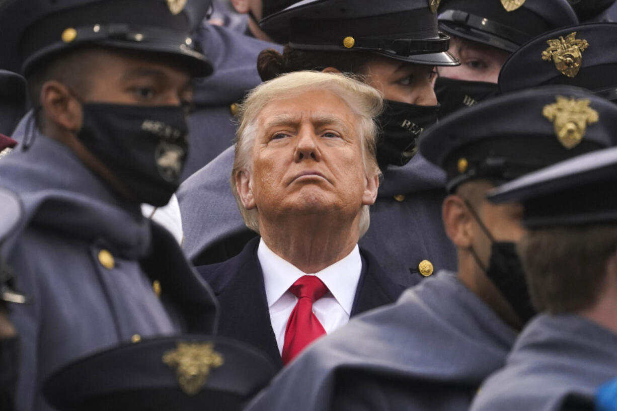 FIlE - Surrounded by Army cadets, President Donald Trump watches the first half of the 121st Army-Navy Football Game in Michie Stadium at the United States Military Academy, Saturday, Dec. 12, 2020, in West Point, N.Y. Experts in constitutional law and the military say the Insurrection Act gives presidents tremendous power with few restraints. Recent statements by former President Donald Trump raise questions about how he might use it if he wins another term.