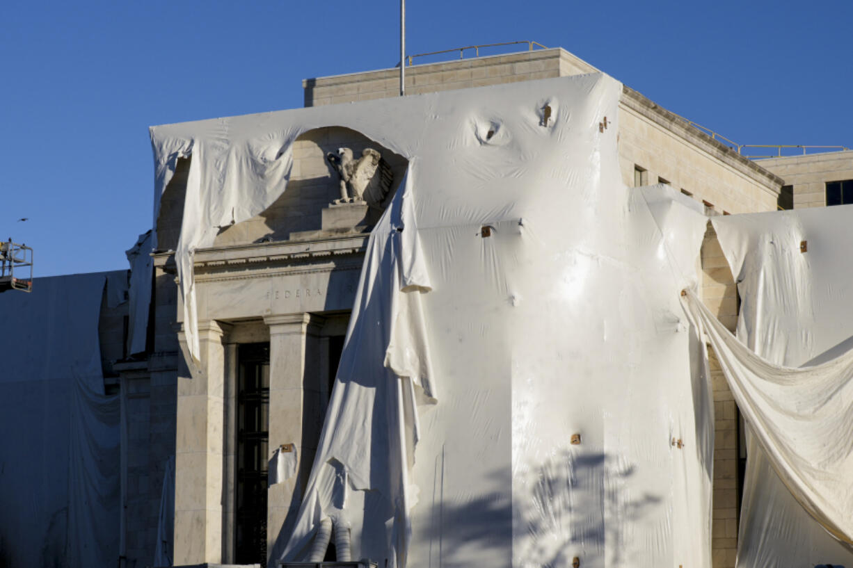 File - The sculpture of an eagle looks out from behind protective construction wrapping on the facade as the Federal Reserve Board Building undergoes both interior and exterior renovations, in Washington, Oct. 23, 2023. The Federal Reserve is expected to leave interest rates alone when its latest meeting ends Wednesday. But economists will be listening closely to what Chair Jerome Powell says about the possible future path for rates. (AP Photo/J.