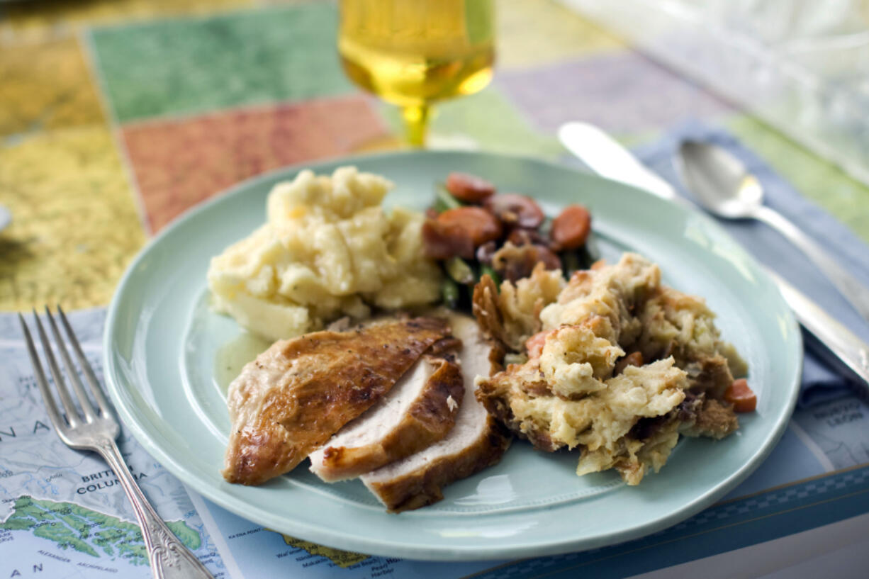 A plate of roasted turkey and gravy, stuffing, mashed potatoes and glazed carrots.