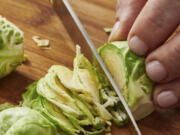 This image provided by Cheyenne Cohen shows Brussel sprouts being sliced on a chopping board. Brussels sprouts are often cooked as a side dish, especially during the cold weather months. They are particularly popular as part of holiday meals such as Thanksgiving and Christmas. And if you think you don&rsquo;t like Brussels sprouts, I&rsquo;m here to say AP food writer Katie Workman says you just haven&rsquo;t had them prepared well.