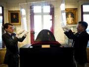 Raphael Pitchal, left, and Jean Christophe Chataignier of Osenat&rsquo;s auction house remove the protection of one of the signature broad, black hats that Napol&eacute;on wore when he ruled 19th century France and waged war in Europe at Osenat&rsquo;s auction house Nov. 17 in Fontainebleau, south of Paris.