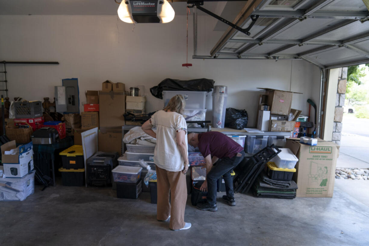 Lonnie Phillips, right, and his wife, Sandy, sift through their belongings stored at a friend's garage in Lone Tree, Colo., Monday, Sept. 4, 2023. Since Sandy's daughter, Jessica Ghawi, was killed in a 2012 mass shooting in a movie theater, the pace of other mass killings only intensified. Instead of tighter gun laws, some states loosened them. Exhausted, disgusted and impoverished, the Phillipses recently moved to Mexico.