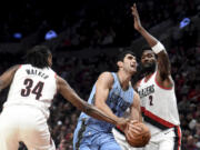 Portland Trail Blazers forward Jabari Walker, left, reaches in as Memphis Grizzlies forward Santi Aldama, center, drives to the basket and Trail Blazers center Deandre Ayton, right, defends during the second half of an NBA basketball game in Portland, Ore., Sunday, Nov. 5, 2023.