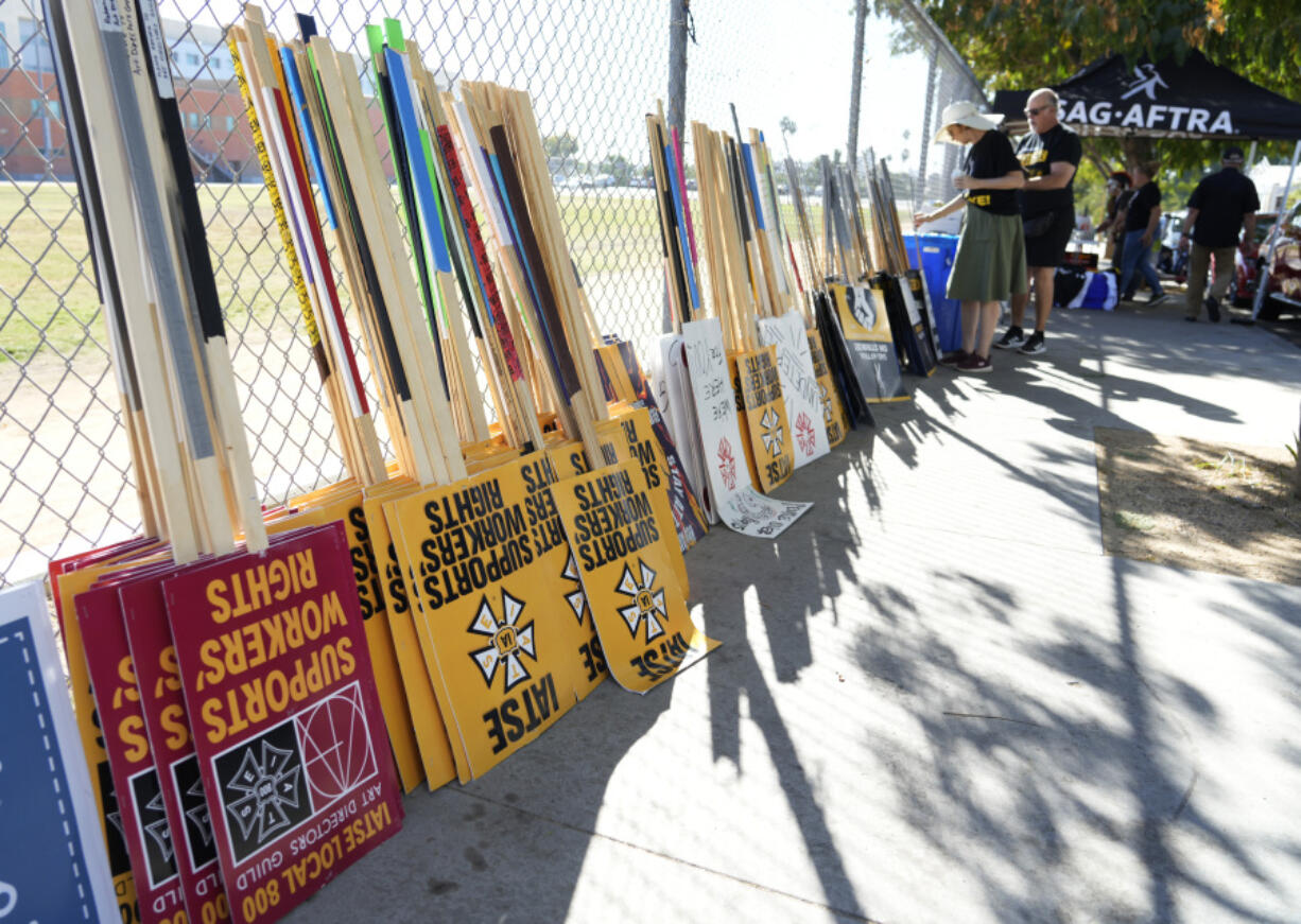 Striking SAG-AFTRA members pick out signs for a picket line outside Netflix studios, Wednesday, Nov. 8, 2023, in Los Angeles.