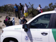 FILE - Asylum-seekers wait in a makeshift camp after crossing the nearby border with Mexico, Sept. 20, 2023, near Jacumba Hot Springs, Calif.  U.S. authorities say illegal border crossings from Mexico fell 14% in October from a month earlier, following three months of big increases. The decline comes during the resumption of deportation flights to Venezuela, shortly after Venezuelans replaced Mexicans as the largest nationality appearing at the border.