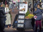 A woman shares Jehovah&rsquo;s Witnesses&rsquo; literature with a passerby Nov. 13 in downtown Pittsburgh. Jehovah&rsquo;s Witnesses regularly distribute literature in public places and do door-to-door evangelism, but for the first time in more than a century, their congregations will not be regularly tracking their hours in ministry.