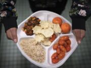 A seventh grader carries her plate which consists of three bean chili, rice, mandarins, cherry tomatoes and baked chips during her lunch break Feb. 10 at a public school in the Brooklyn borough of New York.