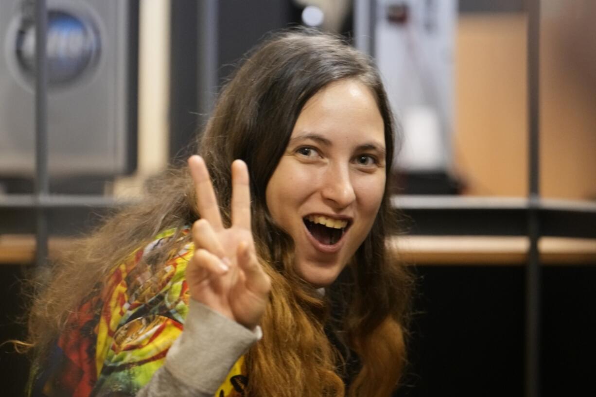 Sasha Skochilenko, a 33 year-old artist and musician gestures standing behind bars in the court room after a hearing in the Vasileostrovsky district court in St. Petersburg, Russia, Monday, Nov. 13, 2023. Skochilenko was arrested in her native St. Petersburg in April 2022, on charges of spreading false information about the military after replacing supermarket price tags with slogans decrying military action in Ukraine. The prosecution last week asked to convict her of the charges and sentence her to eight years in prison.