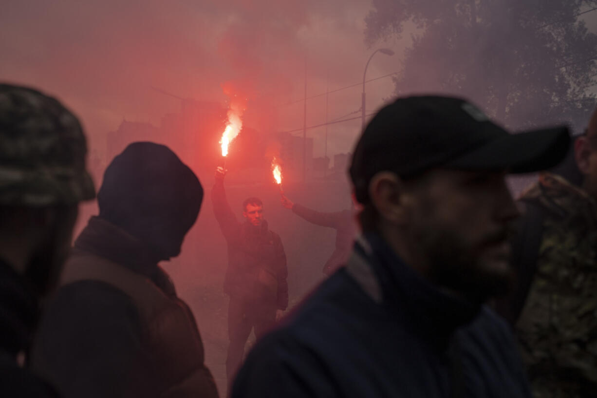 Friends light torches at the burial of Ukrainian soldier Oleksandr Hrianyk in Kyiv, Ukraine, Saturday, Oct. 28, 2023. Hrianyk died in battle in May 2022 in the city of Mariupol, but was only cremated recently after his remains were found and identified.