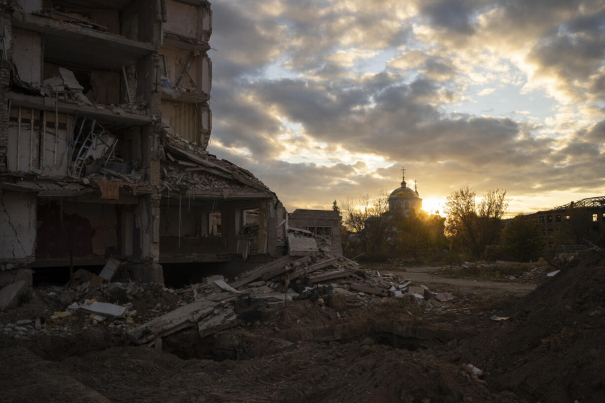 FILE - The sun sets over a destroyed building in Izyum, Ukraine, Tuesday, Oct. 24, 2023.