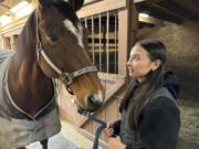 Kylie Ossege looks at her horse, Blaze, at a boarding facility Saturday, Nov. 11, 2023, in Mayfield Township, Mich. Ossege was severely injured in a 2021 mass shooting at Oxford High School and says spending time with Blaze provides her with a measure of comfort.