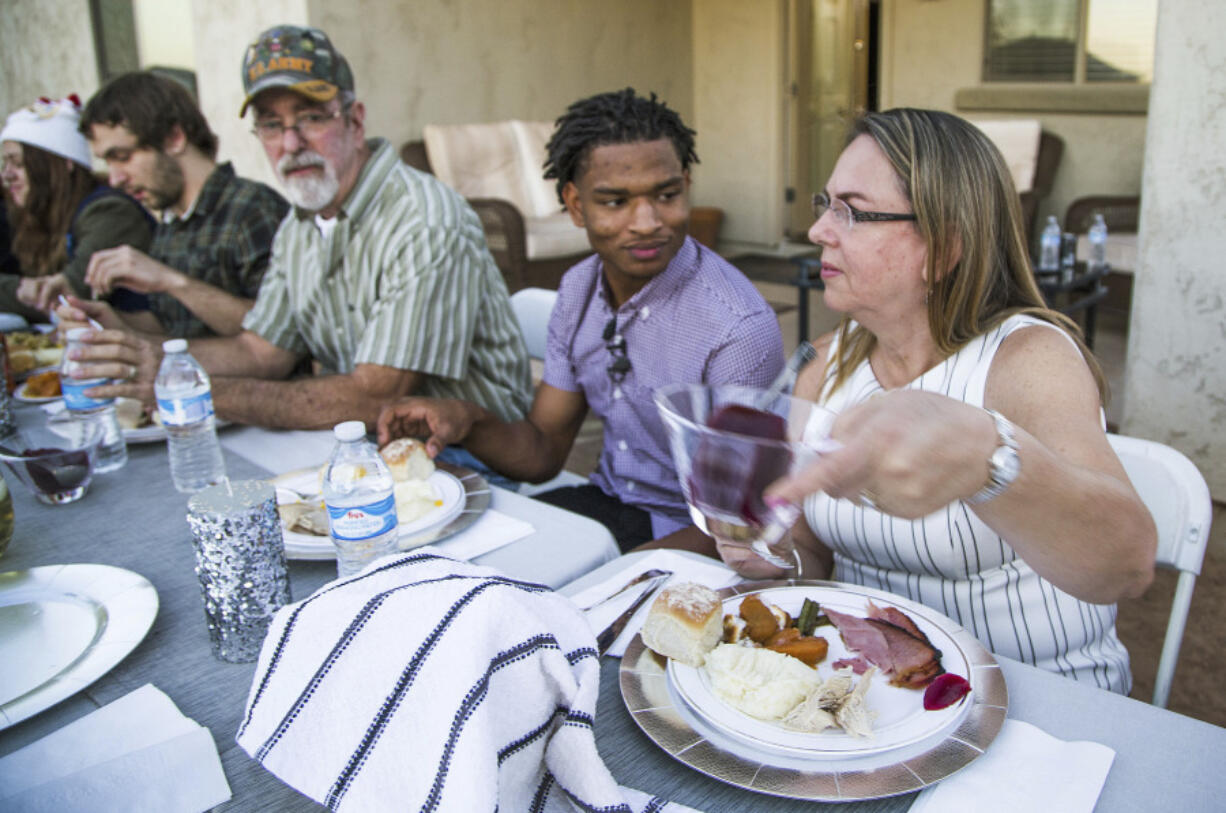 Jamal Hinton, center, Wanda Dench, right, and her family and friends, have Thanksgiving dinner at Dench&rsquo;s home on Nov. 24, 2016, in Mesa, Ariz.