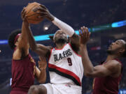 Portland Trail Blazers forward Jerami Grant (9) goes to the basket between Cleveland Cavaliers center Jarrett Allen, left, and forward Evan Mobley during the first half of an NBA basketball game Thursday, Nov. 30, 2023, in Cleveland.