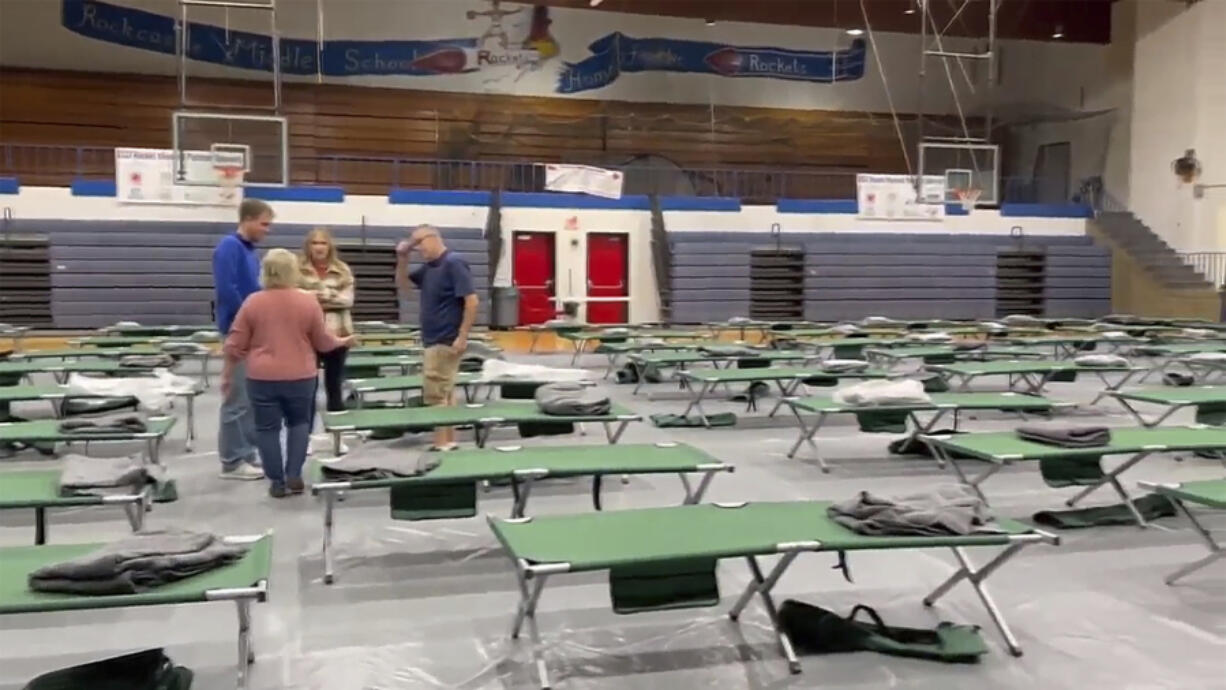 This image taken from video and provided by WTVQ shows people helping arrange cots at Rockcastle Middle School, being used as an evacuation center, in Mt Vernon, Ky., Wednesday, Nov. 22, 2023. People were evacuated from a nearby town after a CSX train derailed Wednesday near Livingston, a remote town with about 200 people in Rockcastle County. CSX says two of the 16 cars that derailed carried molten sulfur, which caught fire after the cars were breached.