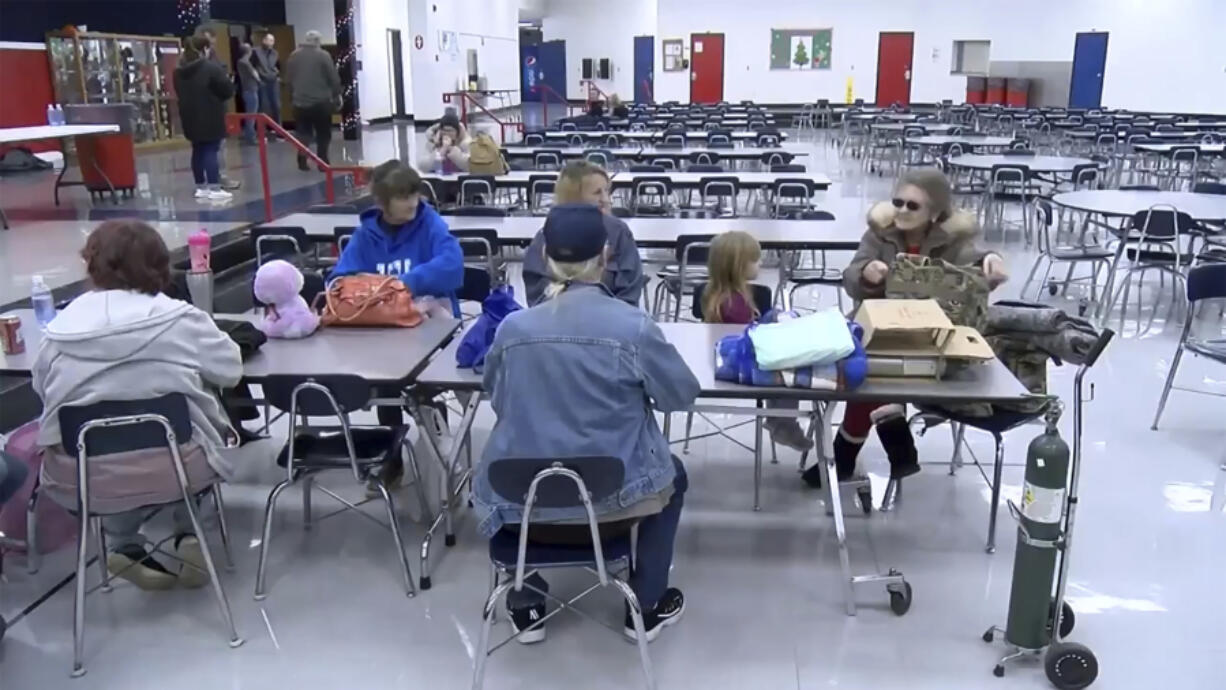 This image taken from video and provided by WTVQ shows people sitting at a table at Rockcastle Middle School being used as an evacuation center in Mt Vernon, Ky., Wednesday, Nov. 22, 2023. People were evacuated from a nearby town after a CSX train derailed Wednesday near Livingston, a remote town with about 200 people in Rockcastle County. CSX says two of the 16 cars that derailed carried molten sulfur, which caught fire after the cars were breached.
