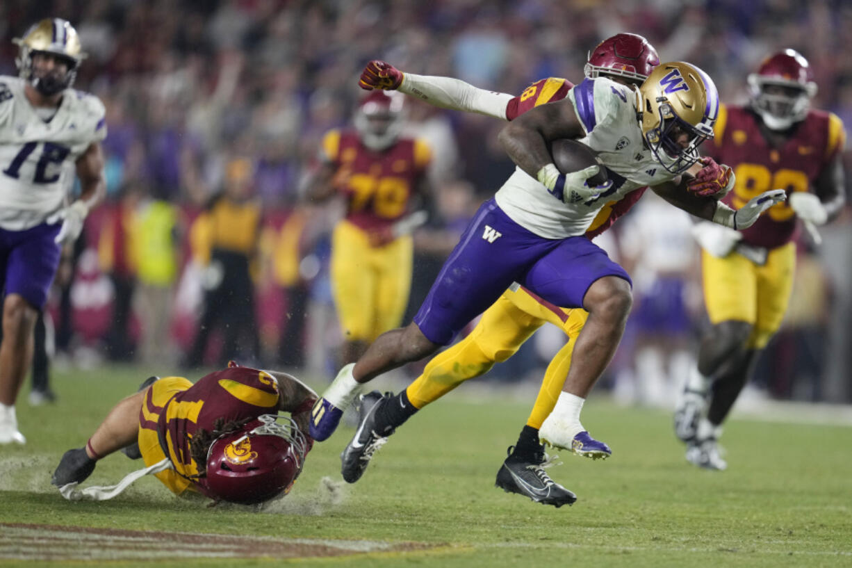 Washington running back Dillon Johnson (7) runs past Southern California linebacker Mason Cobb, bottom left, during the second half of an NCAA college football game Saturday, Nov. 4, 2023, in Los Angeles.