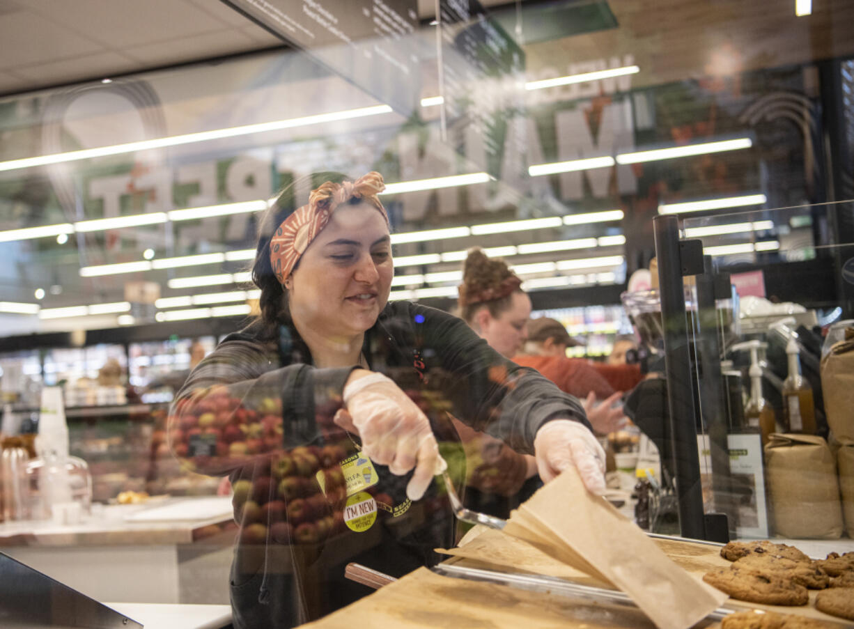 New Seasons Market bakery clerk Kalyea Fanony puts a cookie into a paper bag on Oct. 18 during the grand opening of the downtown Vancouver store.