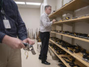 Forensic scientist Johan Schoeman, center, looks over the firearms reference collection at the Washington State Patrol Crime Lab in Vancouver.