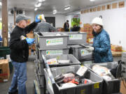 Volunteers Rob Fleskes, left, and Laurie Southwell, both of Vancouver, sort bins of frozen meat Tuesday at the Clark County Food Bank.