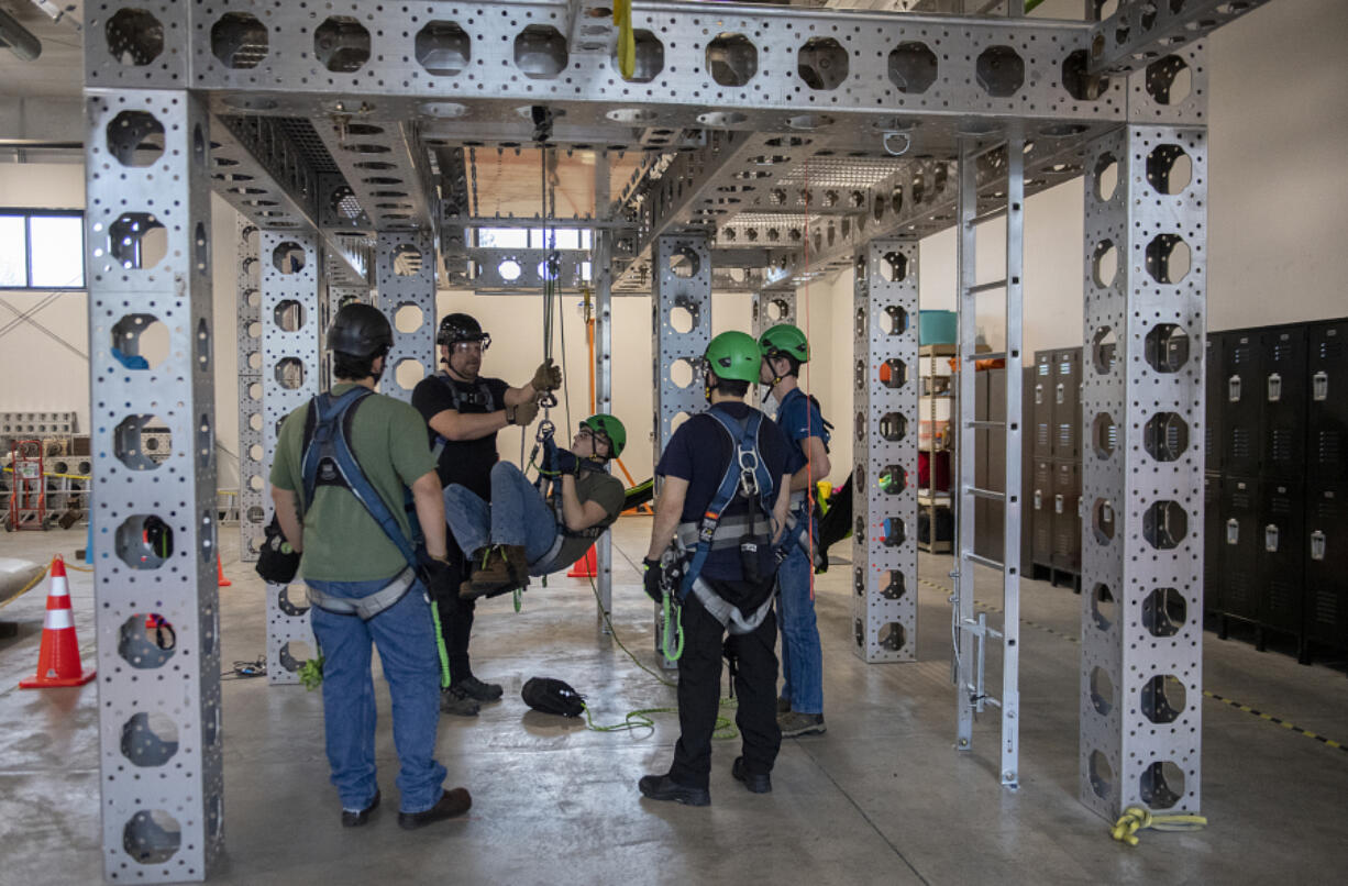 Instructor Tom Bauras, left in black shirt, works with students including Alex Thompson, center, while simulating a cross haul during safety training at the new Northwest Renewable Energy Institute campus in Vancouver on Dec. 20. The business built a new facility on Fruit Valley Road that teaches students how to work on wind turbines.