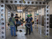 Instructor Tom Bauras, left in black shirt, works with students including Alex Thompson, center, while simulating a cross haul during safety training at the new Northwest Renewable Energy Institute campus in Vancouver on Dec. 20. The business built a new facility on Fruit Valley Road that teaches students how to work on wind turbines.