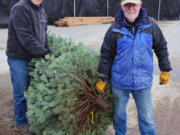 Ridgefield Lions members Steve Withers, left, and David Wright prepare to load a Christmas tree at the Lions&rsquo; tree lot at the Ridgefield Outdoor Recreation Center.