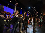 Vancouver School of Arts and Academics students conclude a practice performance with their bows in the air while joined by international recording artist and Emmy award-winning composer Mark Wood, right, in their school&rsquo;s auditorium Jan. 31. Wood is an original member of the multiplatinum selling Trans-Siberian Orchestra and creator of the revolutionary Viper electric violin. He visited VSAA with his groundbreaking music education program Electrify Your Strings!