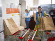 Volunteer Briette Colville, right, readies paper bags for food pantry customers Friday at FISH of Vancouver.