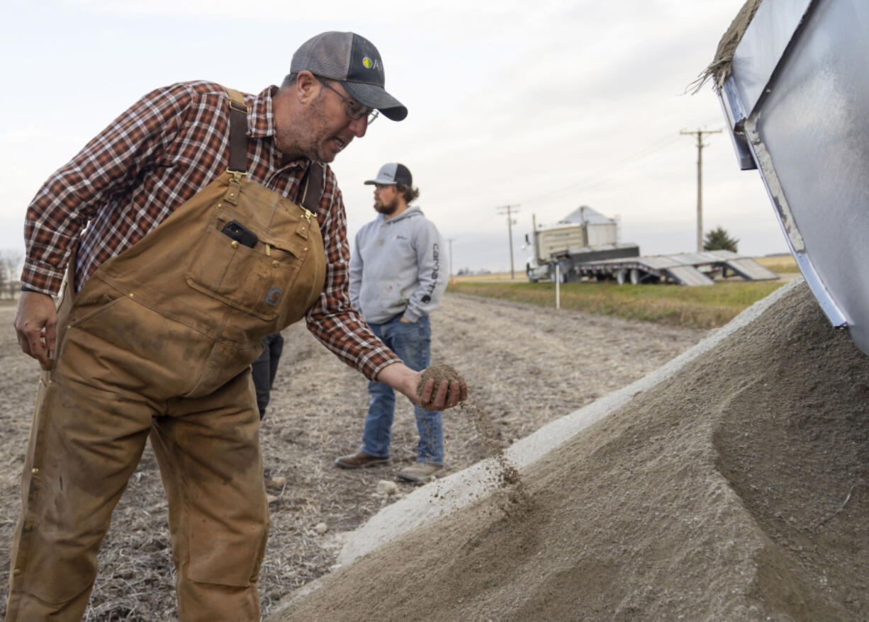 Farmer Erich Schott takes a look at the concrete powder that was spread across his soybean field on Nov. 10, 2023, at Schott Farms in Buckingham, Illinois. The concrete will be tested for efficacy in removing carbon dioxide compared with agricultural lime.