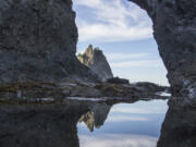 Hole-in-the-Wall, a popular destination at Olympic National Park&rsquo;s Rialto Beach, reflected in a tide pool in 2014.