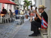 A street performer serenades diners in San Juan, Puerto Rico. Puerto Rico boasts colorful colonial architecture, and free-roaming dogs, horses and chickens lend the island an international feel.