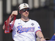 Texas Rangers&#039; Mitch Garver tosses beaded necklaces during a World Series baseball championship parade, Friday, Nov. 3, 2023, in Arlington, Texas. The parade comes two days after the Rangers wrapped up the World Series with a 5-0 win on the road against the Arizona Diamondbacks.