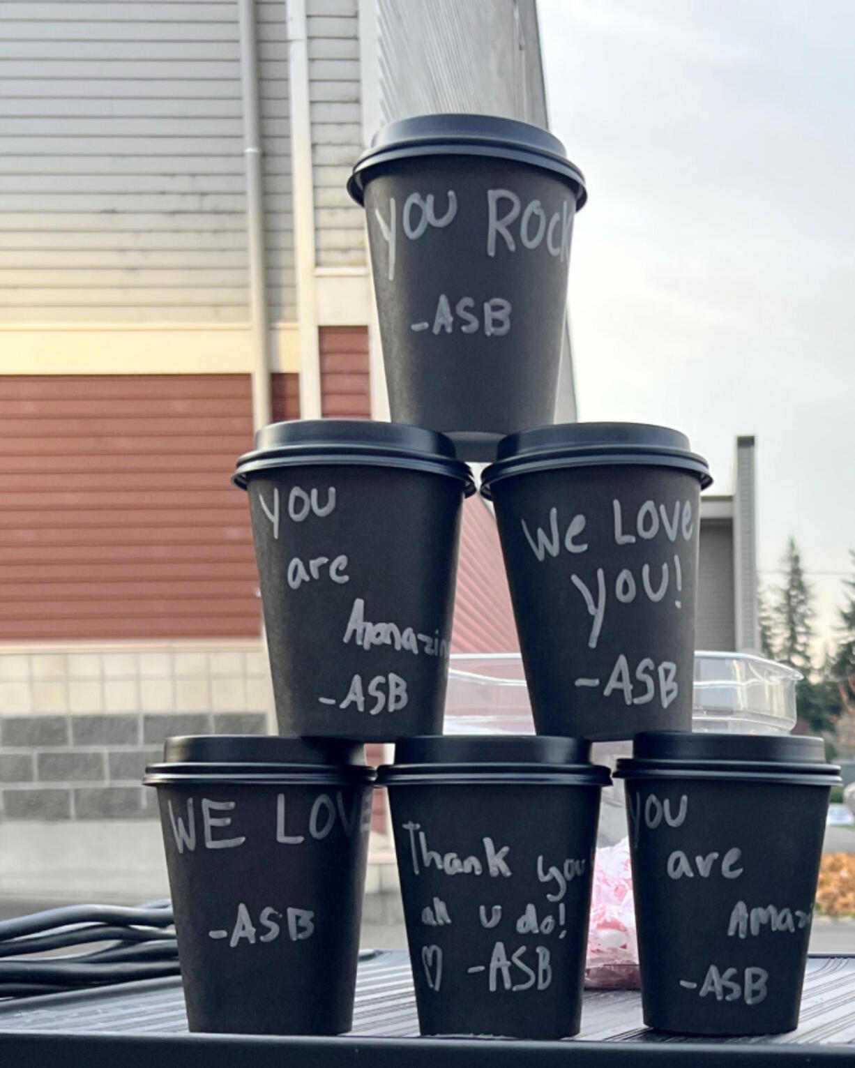 Washougal High School leadership students show off hot chocolate cups, decorated with personalized thank-you messages, before giving them to bus drivers Nov. 21.