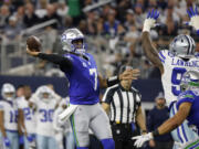 Seattle Seahawks quarterback Geno Smith (7) throws a touchdown pass to DK Metcalf, not pictured, under pressure from Dallas Cowboys defensive end DeMarcus Lawrence (90) in the second half of an NFL football game in Arlington, Texas, Thursday, Nov. 30, 2023.