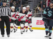 New Jersey Devils left wing Ondrej Palat (18) skates to the bench after scoring a goal, while Seattle Kraken left wing Andre Burakovsky, right, reacts during the first period of an NHL hockey game Thursday, Dec. 7, 2023, in Seattle.