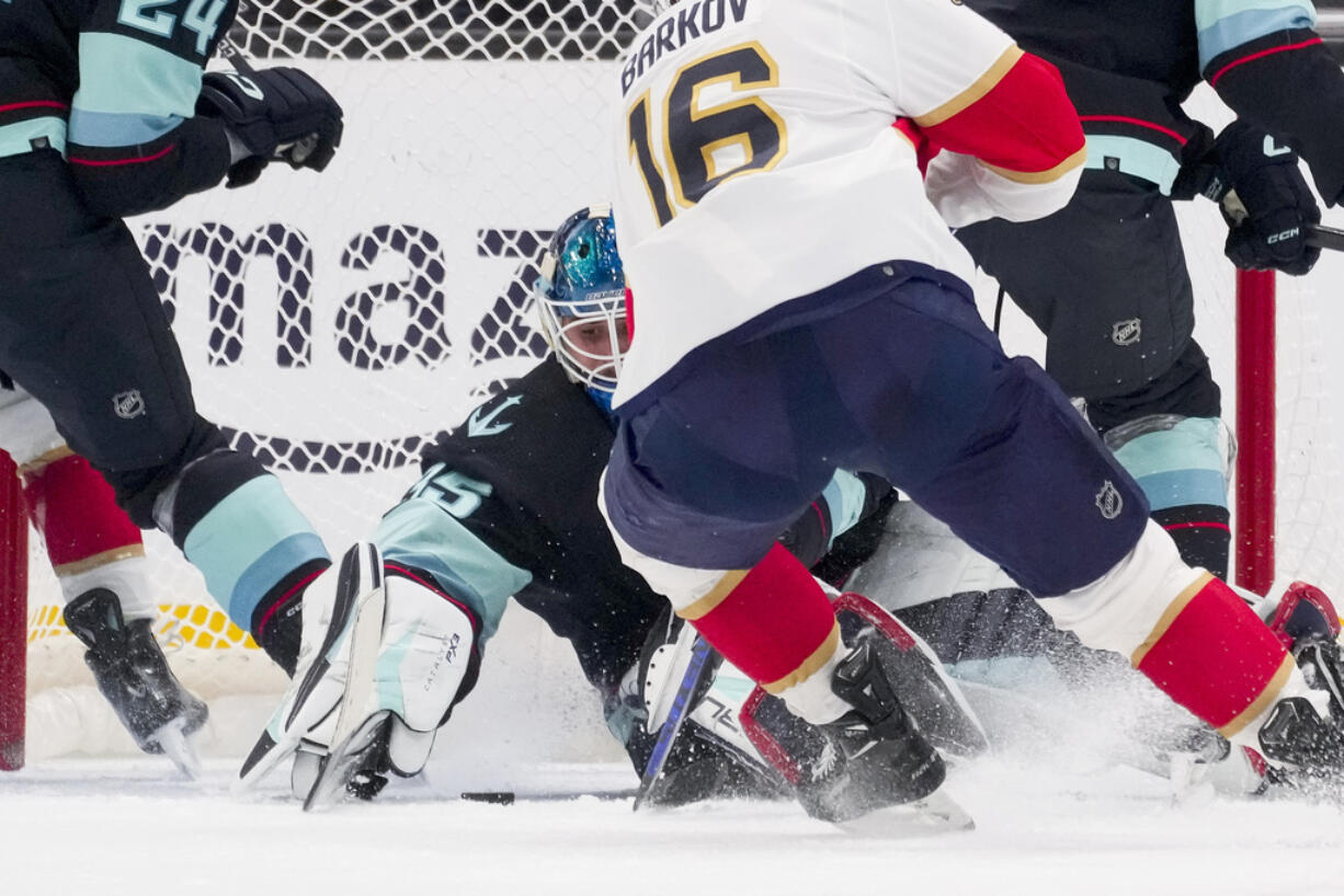 Seattle Kraken goaltender Joey Daccord, center back, makes a save against Florida Panthers center Aleksander Barkov (16) during the first period of an NHL hockey game Tuesday, Dec. 12, 2023, in Seattle.