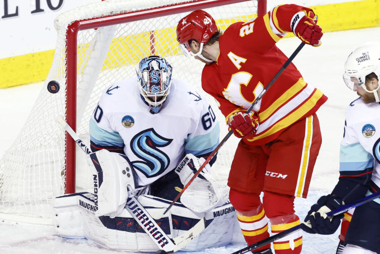 Seattle Kraken goalie Chris Driedger makes a save against Calgary Flames' Elias Lindholm during the third period of an NHL hockey game Wednesday, Dec. 27, 2023, in Calgary, Alberta.