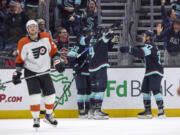 Seattle Kraken defenseman Justin Schultz (4) is congratulated by right wing Oliver Bjorkstrand (22) and center Yanni Gourde (37) after Schultz scored against the Philadelphia Flyers in overtime of an NHL hockey game Friday, Dec. 29, 2023, in Seattle.