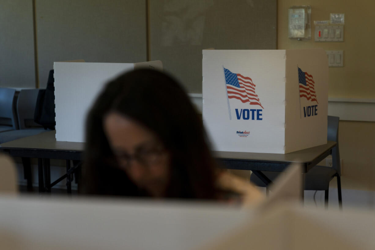 FILE - A voter in the foreground casts her ballots during the Republican primary election in Wilson, Wyo., Aug. 16, 2022. Relatively few Americans are excited about a potential rematch of the 2020 election between President Joe Biden and Donald Trump. But more Republicans would be happy to have Trump as their nominee than Democrats would be with Biden. That&rsquo;s according to a new poll from The Associated Press-NORC Center for Public Affairs Research. (AP Photo/Jae C.