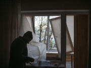 FILE - A man uses plastic to cover a broken window in his apartment following a Russian drone attack in Kyiv, Ukraine, Saturday, Nov. 25, 2023. On Monday, Dec. 4, the Biden Administration sent Congress an urgent warning about the need to approve tens of billions of dollars in military and economic assistance to Ukraine, saying that Kyiv&rsquo;s war effort to defend itself from Russia&rsquo;s invasion may grind to a halt without it.